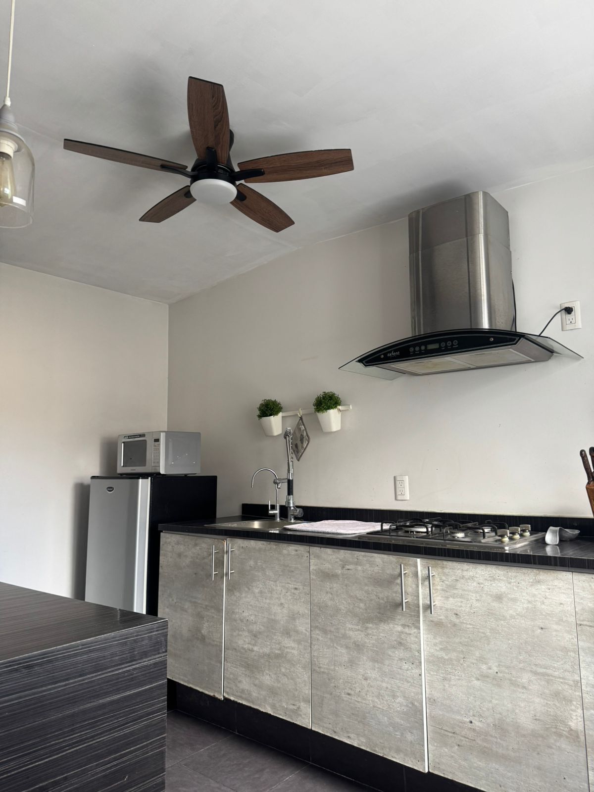 A modern kitchen with a built-in microwave, stainless steel appliances, a ceiling fan, and a gas stove.