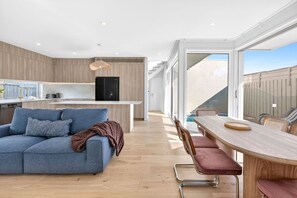 Een moderne keuken met een inbouwkoelkast, een eethoek met een houten tafel en stoelen, en een groot raam met uitzicht op een zwembad.