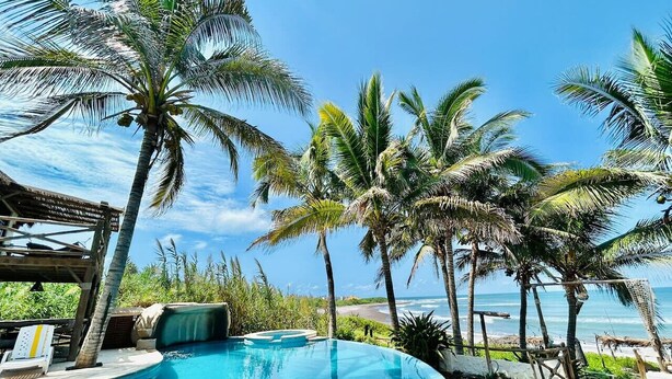 A pool with a view of the ocean, surrounded by palm trees and a wooden structure. - Beach & Pool Getaway by a Partner Host (Celestino Gazca Villaseñor)