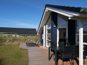 Uma casa moderna com varanda, móveis de exterior e uma janela grande.