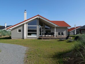 A modern single-story house with a red-tiled roof, large windows, and a covered porch with outdoor seating. - 4 Star Holiday Home in Grossenbrode (Grossenbrode)