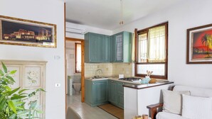 Eine kleine Küche mit türkis-blauen Schränken, einer weißen Arbeitsplatte und einem Essbereich mit einem weißen Sofa und einem kleinen Tisch.