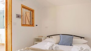 Ein Schlafzimmer mit Bett, Kissen, Nachttisch, Spiegel und Fenster.