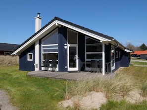 Ett modernt hus med en stor glasdörr, en inglasad uteplats och husnummer 116.