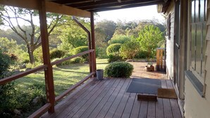 Une terrasse en bois offrant une vue sur un jardin aménagé et un bâtiment.