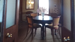 Un coin repas comprenant une table ronde, quatre chaises, un vase avec des fleurs et une fenêtre laissant entrer la lumière naturelle.