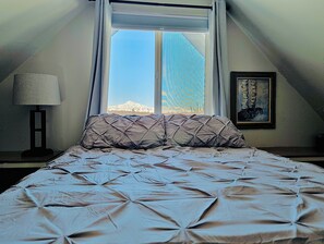 Un dormitorio con cama, ventana, lámpara y un cuadro.