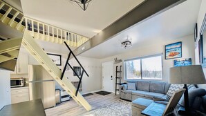Ein modernes Interieur mit Treppe, einer Couch, einem Couchtisch, einer Lampe und einem großen Fenster.