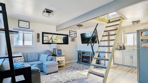 Ein modernes Wohnzimmer mit einer Couch, einem Fernseher, einem Kamin und einer einzigartigen Wendeltreppe.
