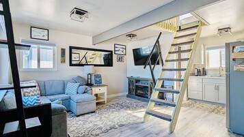 A modern living room with a sofa, a TV, a fireplace, and a unique spiral staircase.