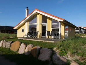 A yellow building with a red roof, large windows, and outdoor seating.