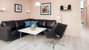 A modern living room with a leather sofa, a white coffee table, a black chair, and wooden walls.