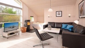 A modern living room with a sofa, a chair, a TV, a fireplace, and a dining table.