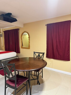 A dining area with a round table, four chairs, a mirror, and two curtains. - Soothing 1-bedroom apartment with AC in vibrant Las Vegas (Las Vegas)