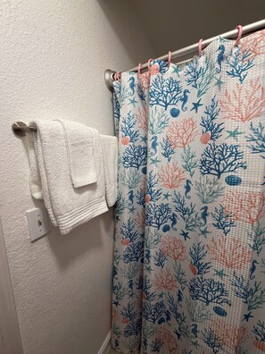 A bathroom with a white towel rack, a white towel, and a shower curtain with a seahorse and coral pattern. - Soothing 1-bedroom apartment with AC in vibrant Las Vegas (Las Vegas)