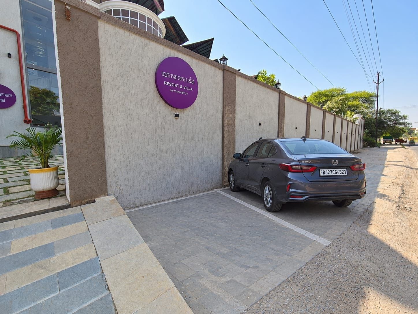 Un coche aparcado frente a un edificio con un cartel que indica un complejo turístico y villas.