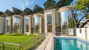 Un hôtel moderne doté d’une piscine, de grandes fenêtres et d’une pelouse bien entretenue.