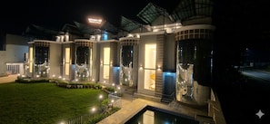 A modern hotel with a well-lit entrance, a pool area, and a sign indicating the name 'Rocaby Villa.'
