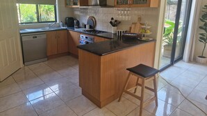 A kitchen with wooden cabinets, a dishwasher, a stove, and a large window. - Beautiful family home ,fully furnished in Bendigo over Easter 3rd April  to 8th (Strathdale)