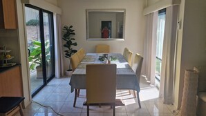 A dining area with a table, chairs, a potted plant, and a view through a glass door. - Beautiful family home ,fully furnished in Bendigo over Easter 3rd April  to 8th (Strathdale)