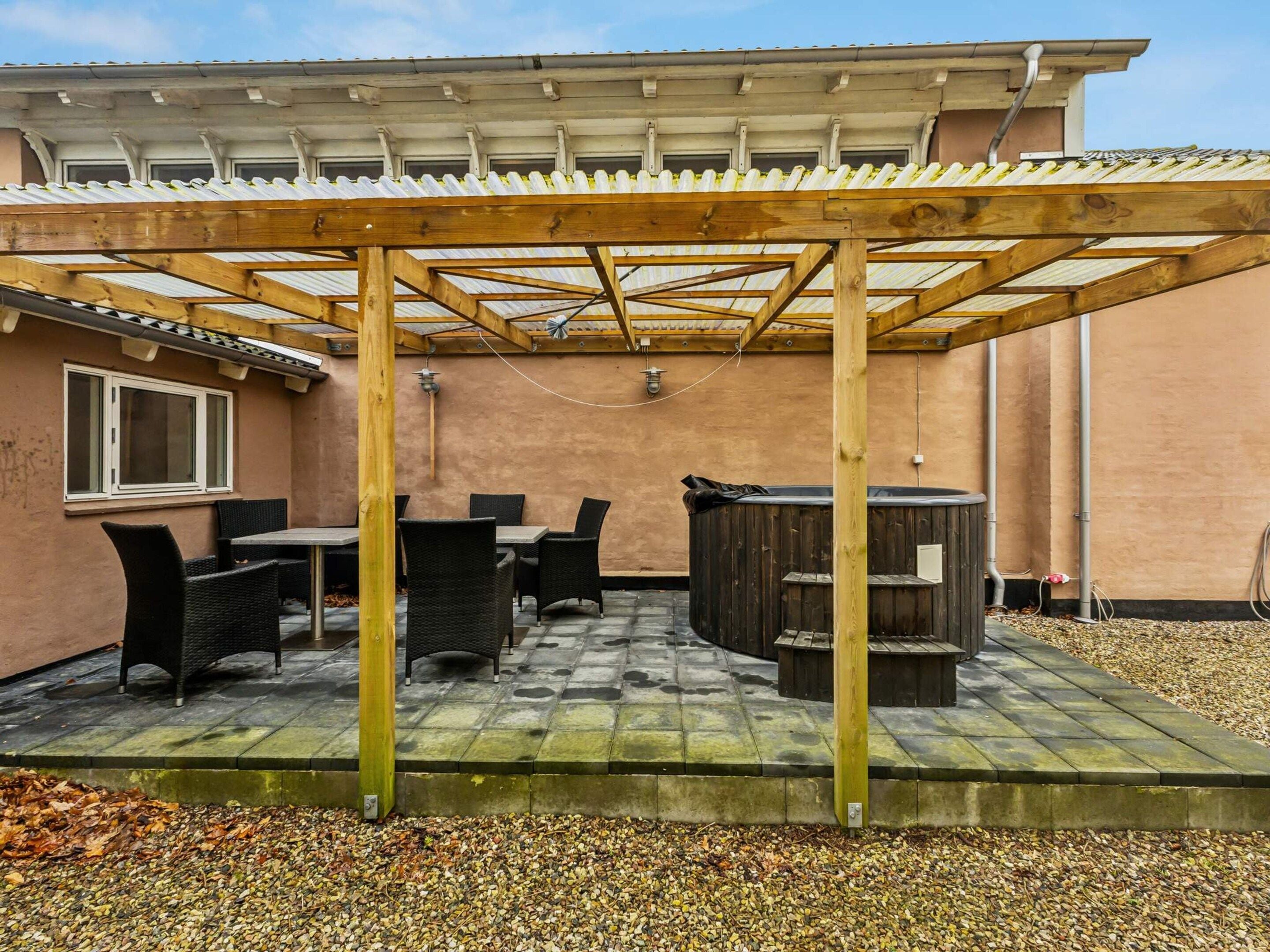 A covered patio with outdoor furniture, a barbecue grill, and a pergola structure.
