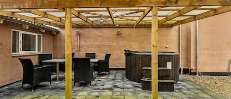 A covered patio with outdoor furniture, a barbecue grill, and a pergola structure.
