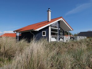 A single-story house with a red-tiled roof, a chimney, and a white balcony railing. - 4 Star Holiday Home in Grossenbrode (Grossenbrode)