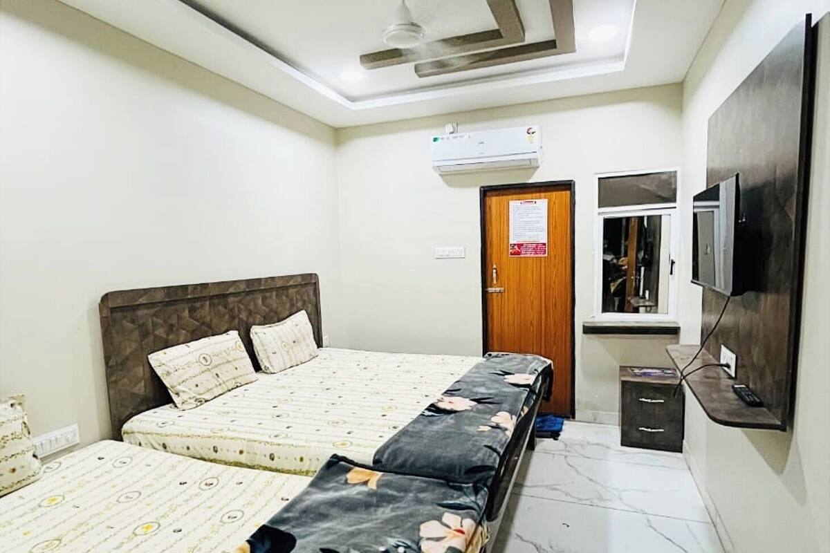 Un dormitorio con dos camas, un armario, un televisor y aire acondicionado.