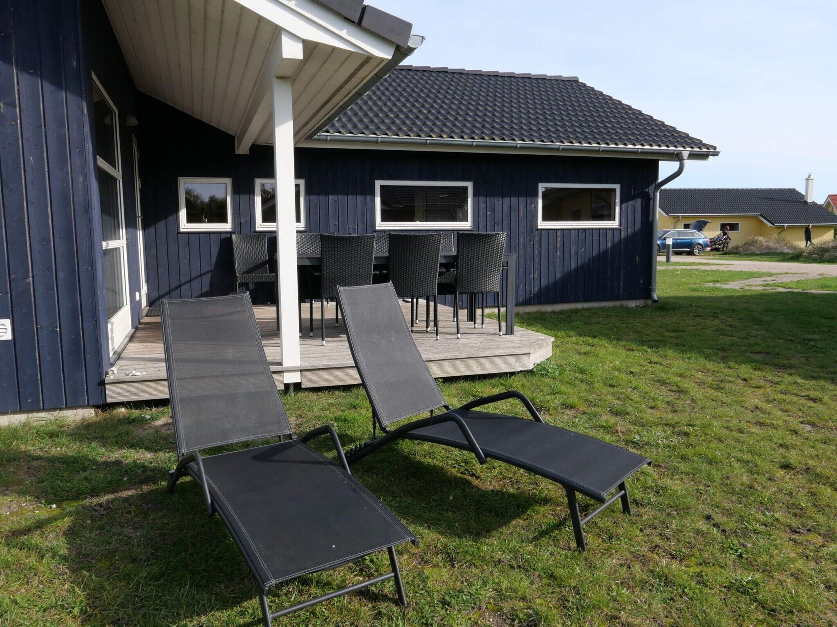 A house with a covered porch, outdoor seating, and a car in the background.