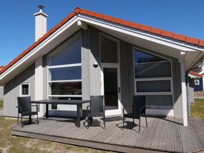 A modern building with a sloped roof, large windows, and a deck with outdoor seating. - 4 Star Holiday Home in Grossenbrode (Grossenbrode)