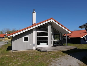 A modern single-story house with a red-tiled roof, a chimney, and a covered porch with outdoor seating. - 4 Star Holiday Home in Grossenbrode (Grossenbrode)