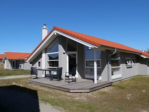 A modern house with a sloped roof, large windows, and a deck with outdoor furniture. - 4 Star Holiday Home in Grossenbrode (Grossenbrode)