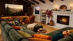 Una sala de estar acogedora con chimenea, sofás verdes y una televisión.