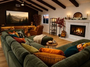 Ein gemütliches Wohnzimmer mit Kamin, grünen Sofas und einem Fernseher.