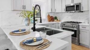 Una cocina moderna con armarios blancos, una isla central con pileta, estufa y microondas.