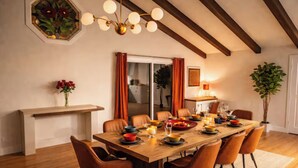 Comedor con mesa de madera, seis sillas, candelabro, espejo y planta en maceta.