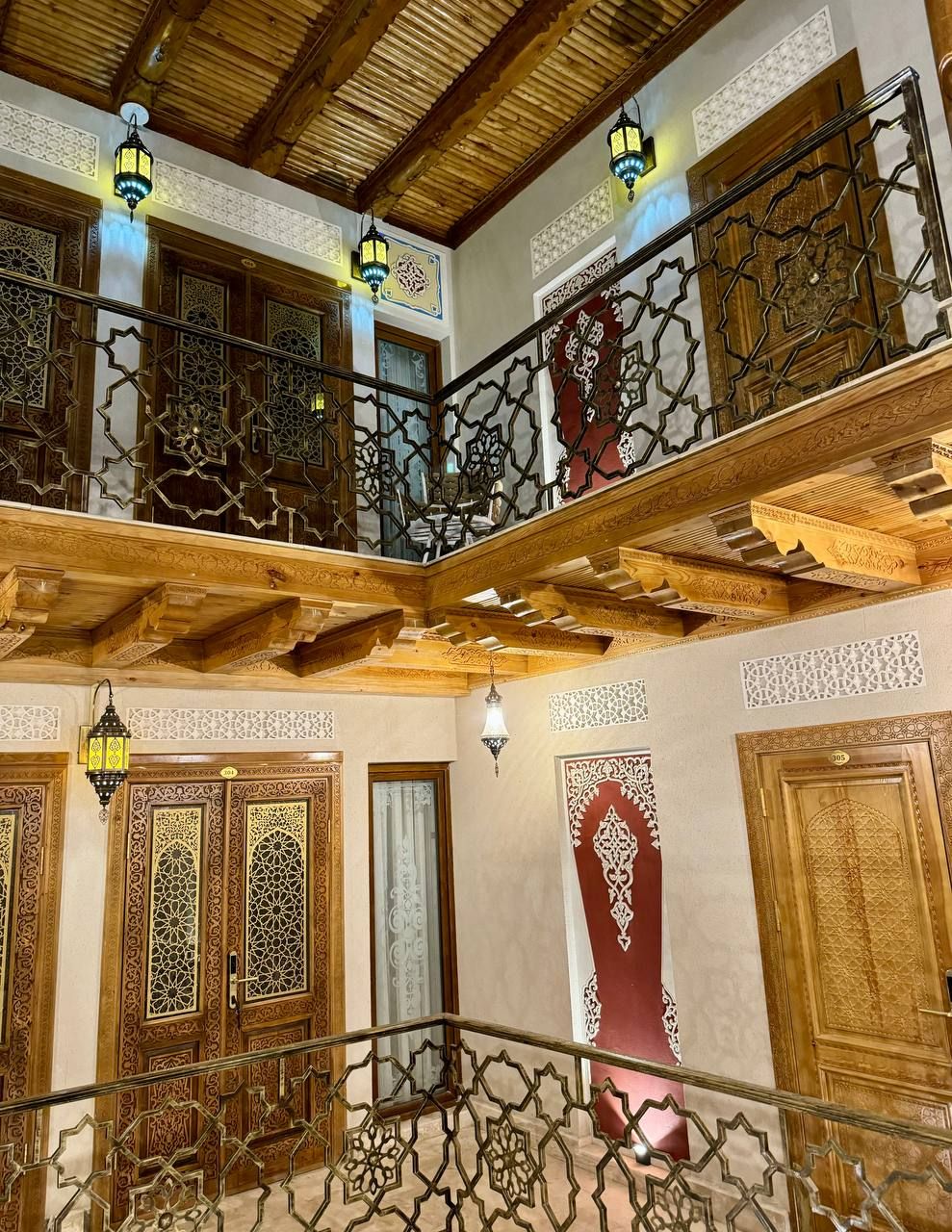Un intérieur à plusieurs niveaux, agrémenté de balcons en bois richement décorés, de rampes de fer forgé complexes et d’éléments décoratifs traditionnels.