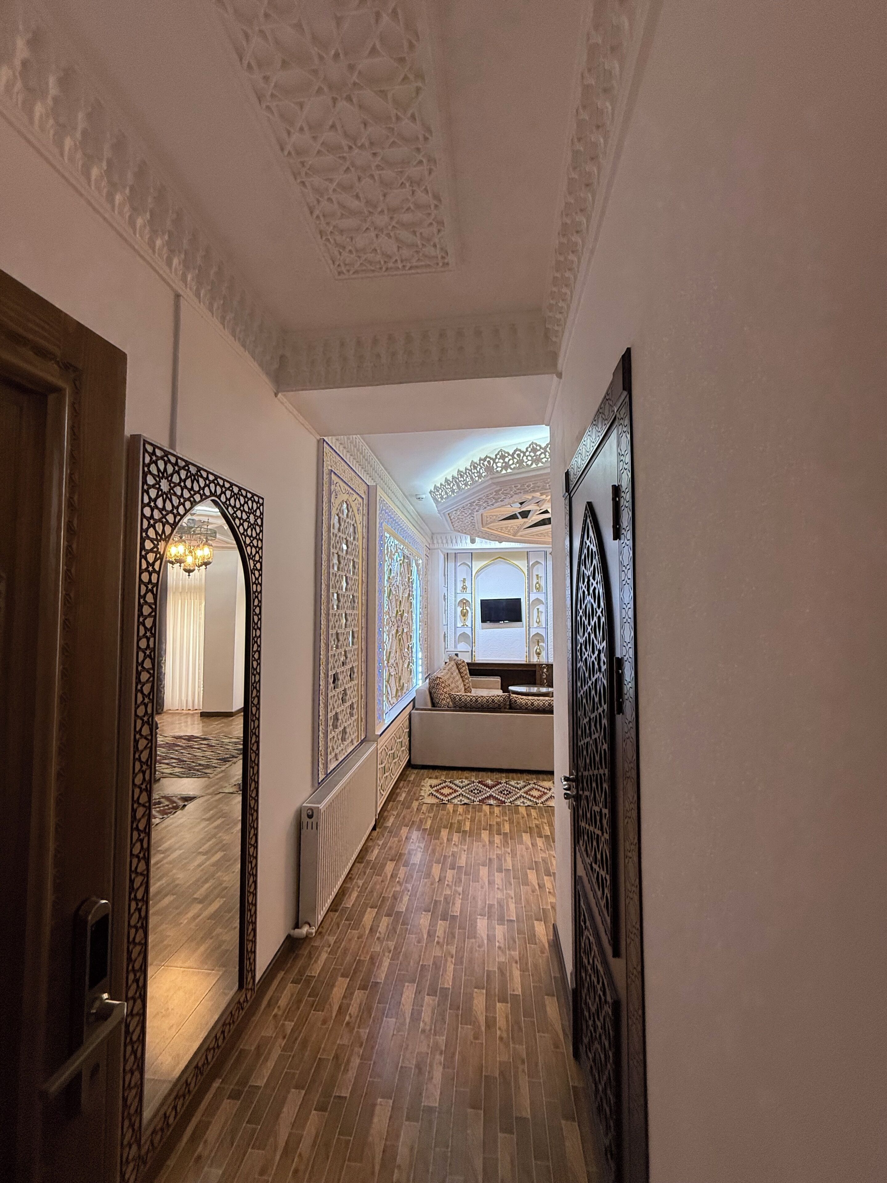 A hallway with patterned walls, a wooden floor, and a seating area with cushions.