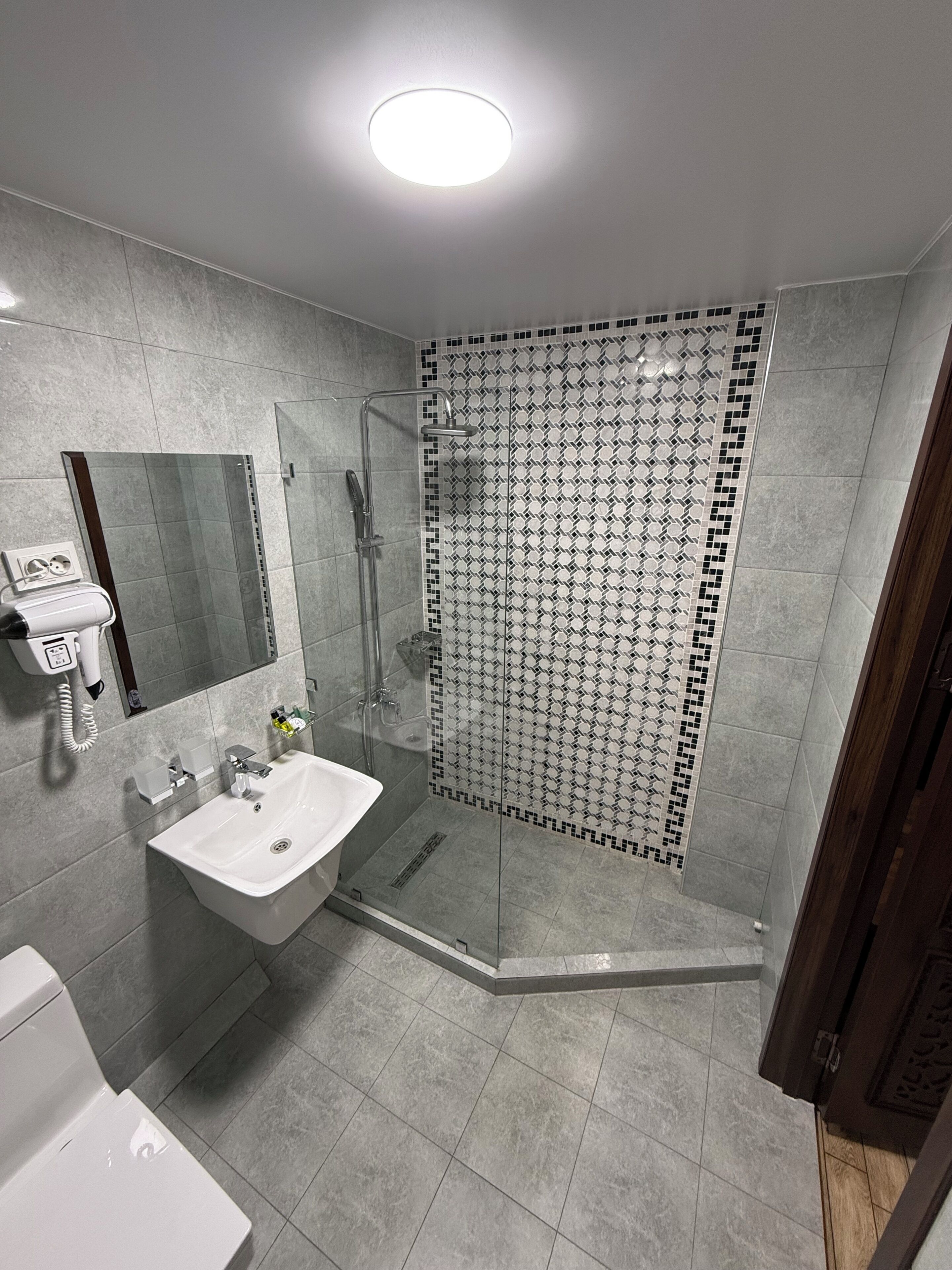 A modern bathroom with a glass-enclosed shower, a white sink, and a mirror.