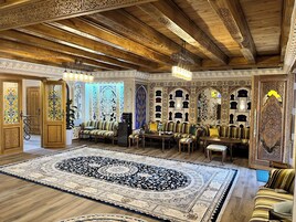A room with a large ornate rug, wooden furniture, and intricate wall decorations.