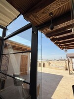 Una habitación con un ventanal grande, una puerta de madera y vistas a un patio con arquitectura tradicional.