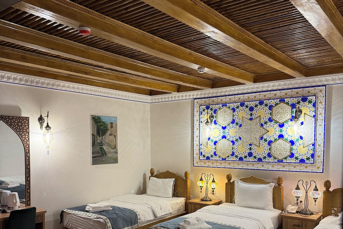 A room with three wooden beds, a desk, and a patterned rug.