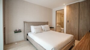 A bedroom with a bed, bedside tables, a nightstand, a wooden wardrobe, and a door leading to a bathroom. - Casa Monroy en Roma Norte - LowF (Ciudad de México)