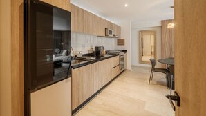 A modern kitchen with a built-in microwave, stove, and oven, wooden cabinetry, and a dining area with a table and chairs. - Casa Monroy en Roma Norte - LowF (Ciudad de México)