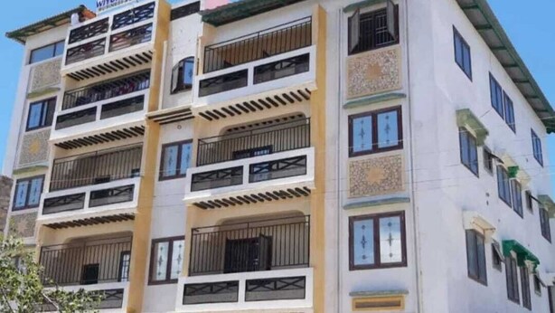 Un edificio de varios pisos con balcones, un letrero que dice 'Wiyoni Royals' y una entrada con rejas.