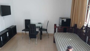 Una habitación con una cama, un escritorio con una silla, un televisor y una ventana con cortinas.