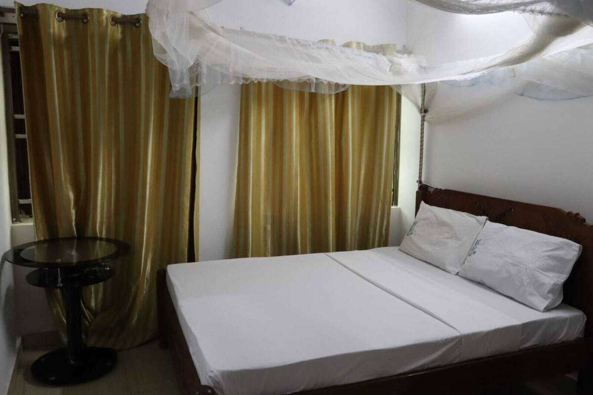 Una cama con ropa blanca, una mesa redonda y cortinas.
