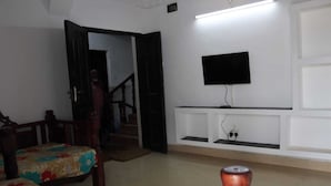 Una habitación con una cama, un televisor montado en la pared, una escalera y una puerta que da a otra estancia.