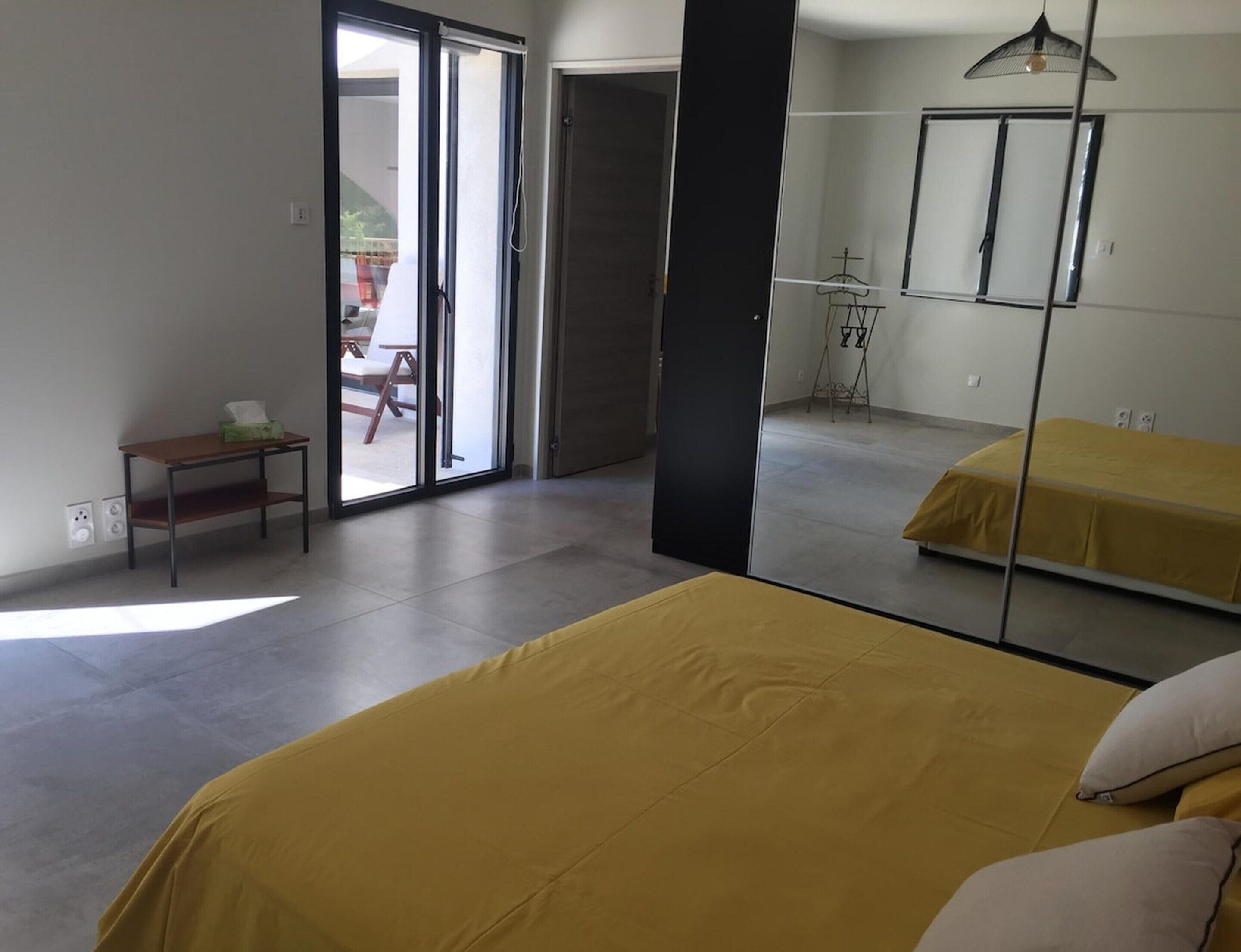 Une chambre avec deux lits, une petite table, une chaise et un grand miroir.