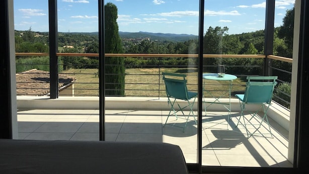 Un balcon donnant sur un paysage rural, avec une table et deux chaises.